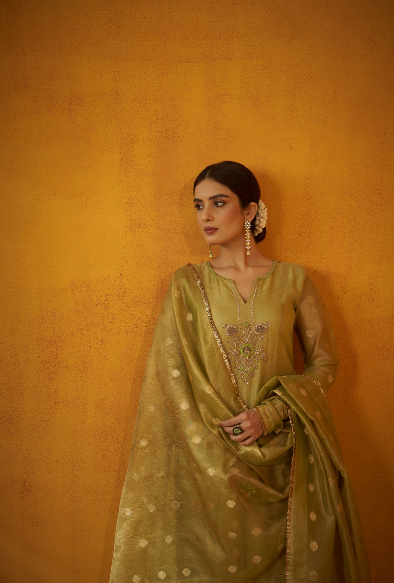 A woman wearing a green anarkali set with zardosi handwork and paired with green silk pants and a dupatta.