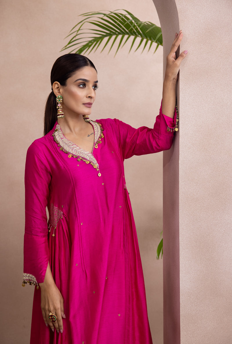 A woman wearing a pink A-line kurta set with leaf buta in zardozi and tikki detail on hem and cuffs.