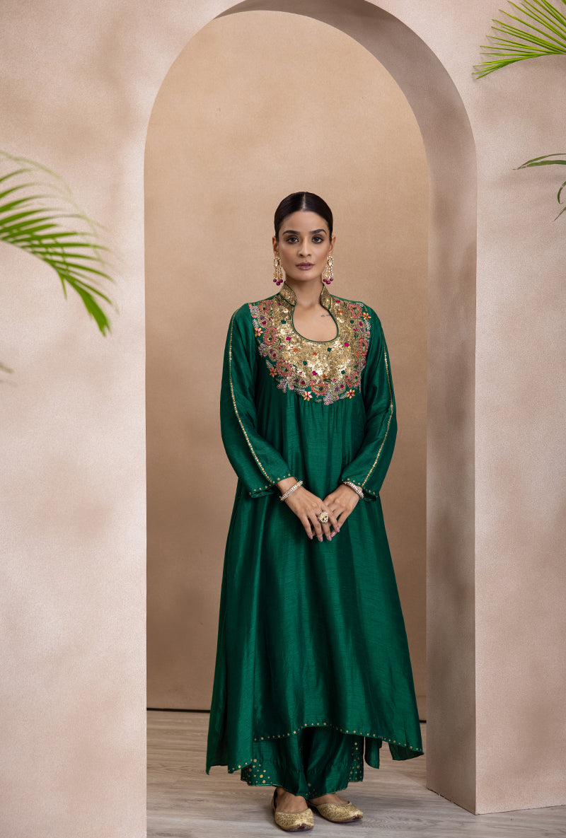 A woman wearing a green kurta set with matka neckline and zardozi resham kairi and gota flowers on the yoke, paired with matching lowers and tikki work.