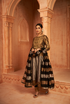 Gold yoke tissue metallic Anarkali set with embroidered details and striped dupatta, elegantly posed in a traditional setting.