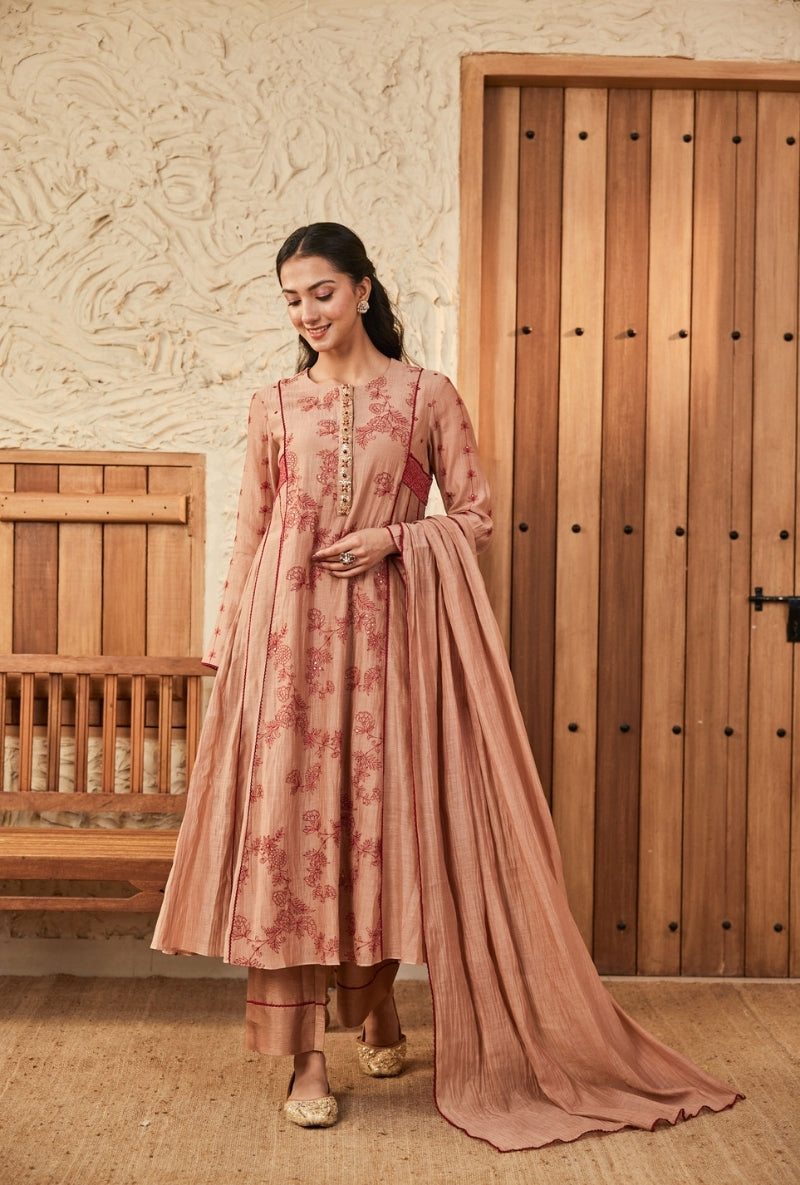 Woman in a traditional outfit standing in front of a wooden door.