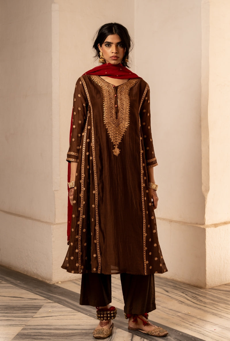 Woman wearing a brown and red traditional outfit with intricate patterns.