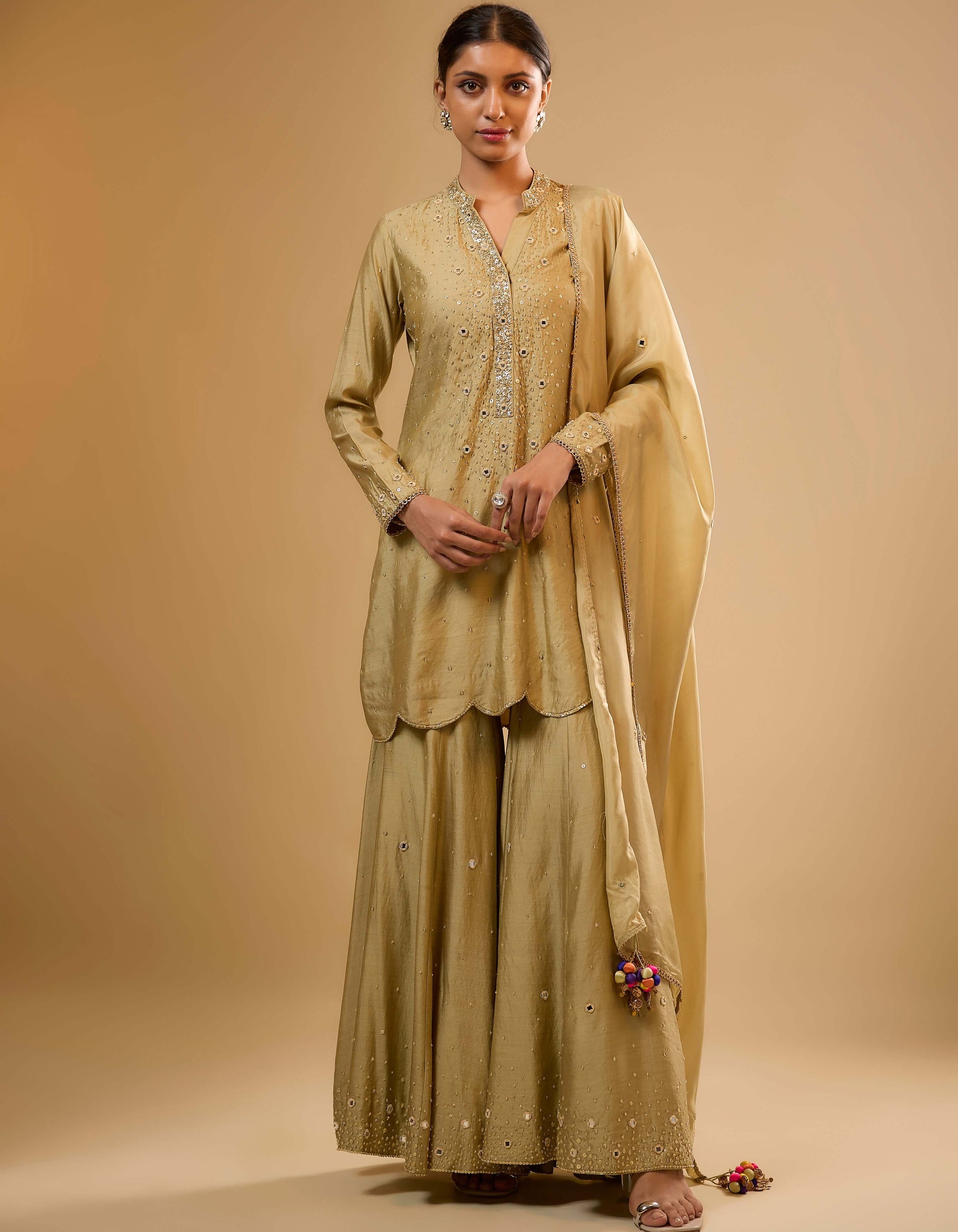 Woman wearing a traditional beige outfit with a shawl on a beige background