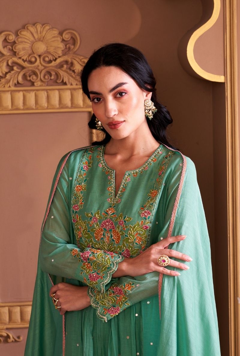Woman wearing a green embroidered traditional outfit in an ornate setting
